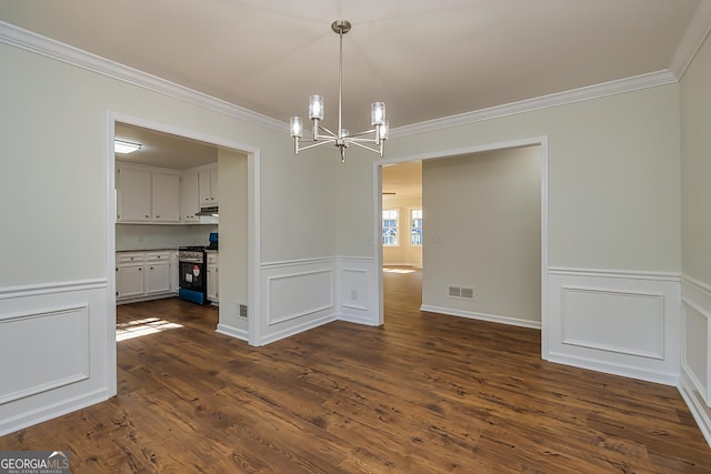 unfurnished dining area featuring crown molding, dark hardwood / wood-style floors, and an inviting chandelier