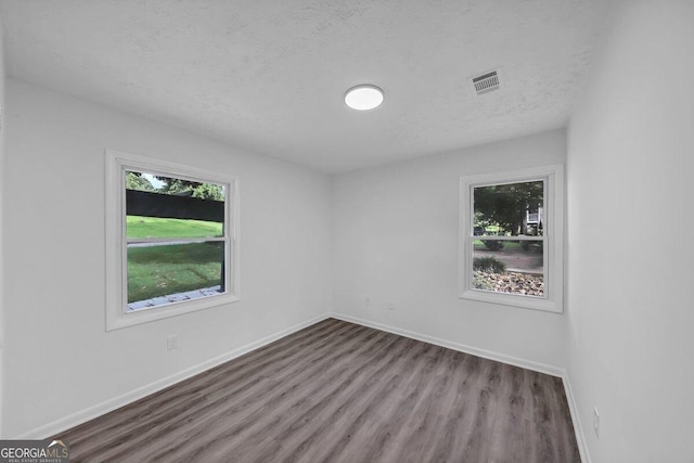 empty room with hardwood / wood-style floors and a textured ceiling