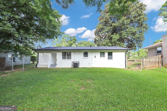 back of property with a yard and central AC