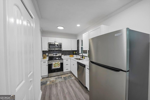 kitchen featuring white cabinetry, ornamental molding, appliances with stainless steel finishes, and sink