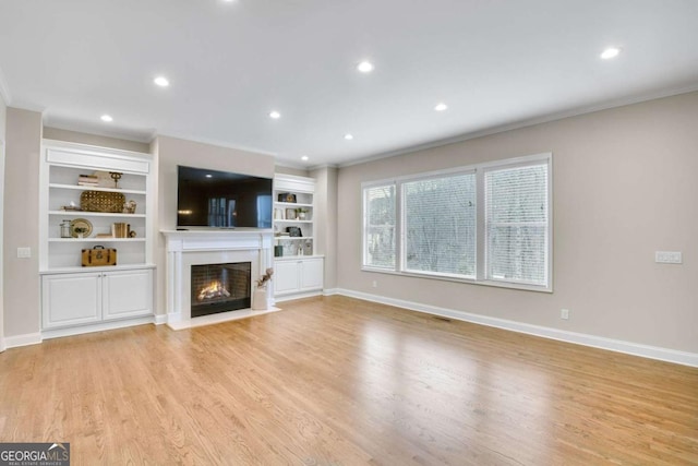 unfurnished living room featuring ornamental molding, light wood-type flooring, and built in shelves