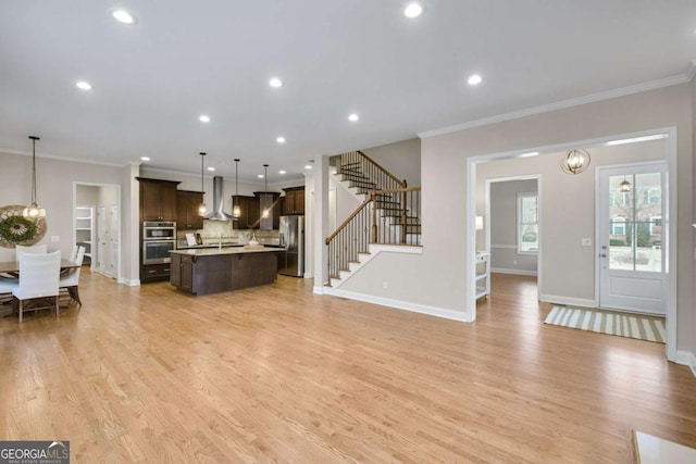 living room with crown molding, an inviting chandelier, and light wood-type flooring