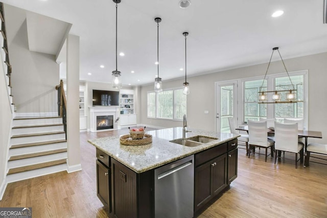 kitchen with sink, dark brown cabinets, a center island with sink, dishwasher, and light stone countertops