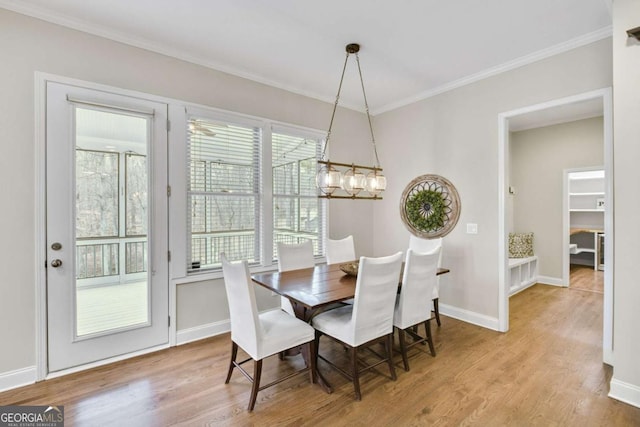 dining space featuring crown molding, a chandelier, and light hardwood / wood-style flooring