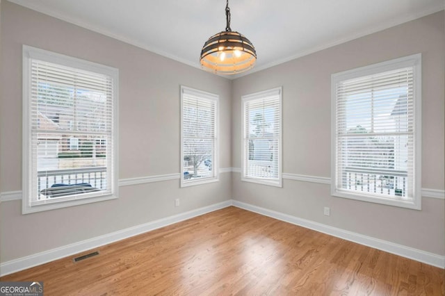 empty room featuring hardwood / wood-style flooring, crown molding, and plenty of natural light