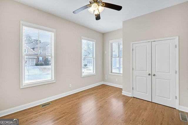 unfurnished bedroom with ceiling fan, light wood-type flooring, and a closet