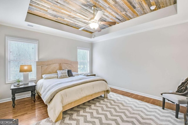 bedroom with crown molding, wood ceiling, light hardwood / wood-style flooring, ceiling fan, and a raised ceiling