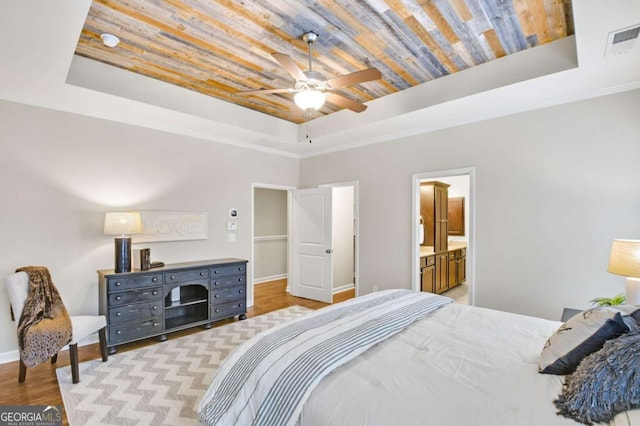 bedroom with ensuite bathroom, wood ceiling, crown molding, light wood-type flooring, and a tray ceiling