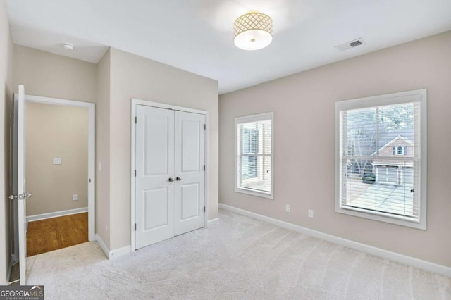 unfurnished bedroom featuring light carpet and a closet