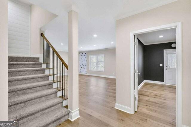 stairs featuring crown molding and hardwood / wood-style flooring