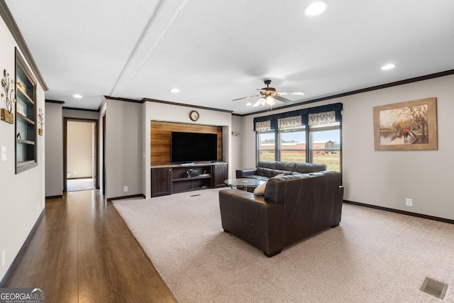 living room featuring ceiling fan, ornamental molding, hardwood / wood-style floors, and a textured ceiling