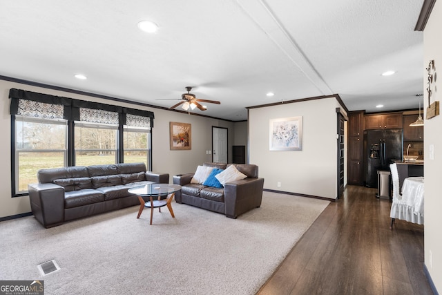 living room with dark hardwood / wood-style flooring, crown molding, and ceiling fan