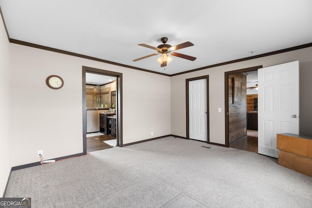 interior space with crown molding, connected bathroom, dark carpet, and ceiling fan