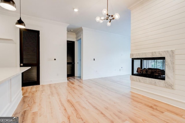 unfurnished living room with crown molding, a multi sided fireplace, a chandelier, and light hardwood / wood-style floors