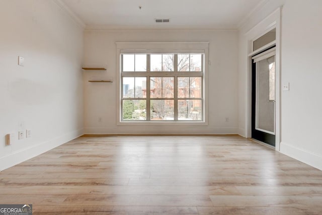 spare room featuring crown molding and light hardwood / wood-style flooring