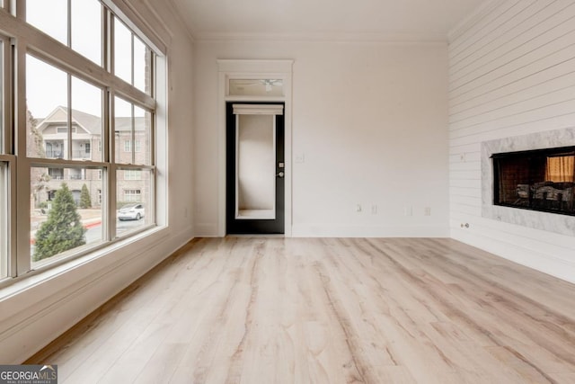 unfurnished living room with crown molding, plenty of natural light, and light hardwood / wood-style flooring