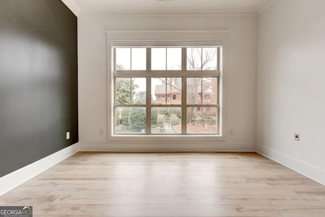 spare room with ornamental molding, a healthy amount of sunlight, and light wood-type flooring