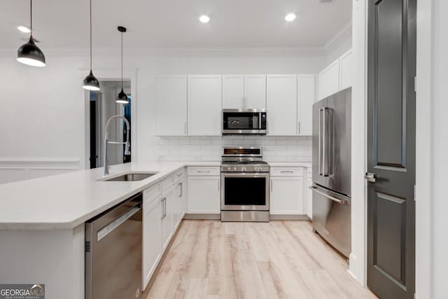 kitchen featuring sink, white cabinetry, appliances with stainless steel finishes, kitchen peninsula, and pendant lighting