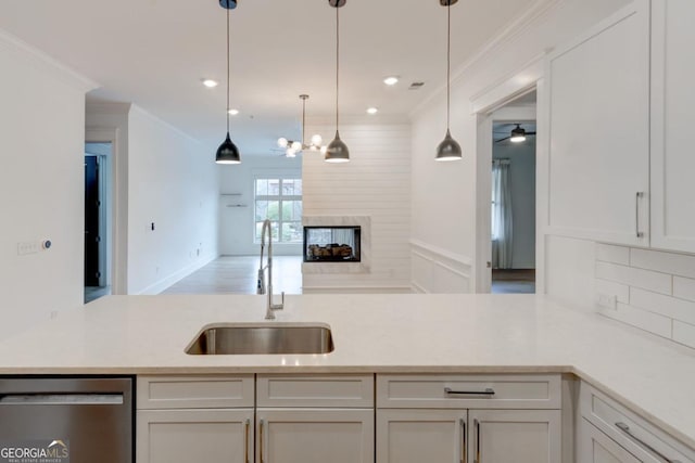 kitchen with white cabinetry, crown molding, sink, and stainless steel dishwasher