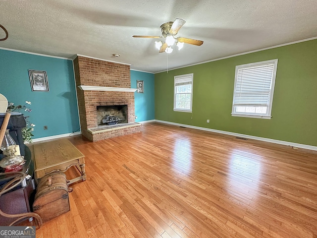 living room featuring crown molding, ceiling fan, a fireplace, and light hardwood / wood-style floors