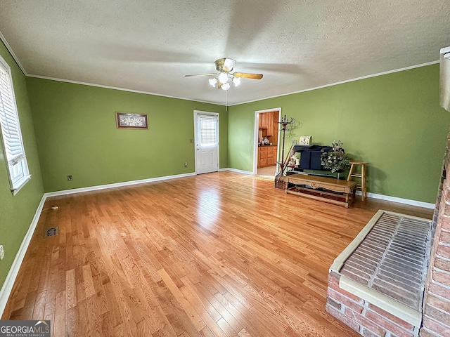 unfurnished living room featuring ornamental molding, wood-type flooring, and a textured ceiling