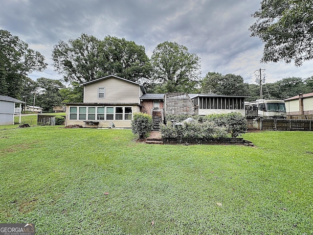 rear view of property featuring a yard and a sunroom