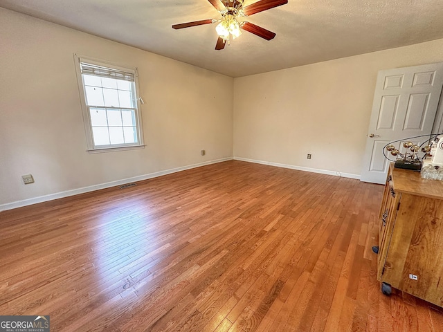 empty room with ceiling fan, a textured ceiling, and light hardwood / wood-style floors