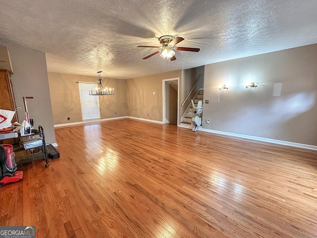 living room featuring ceiling fan with notable chandelier, a textured ceiling, and light hardwood / wood-style flooring