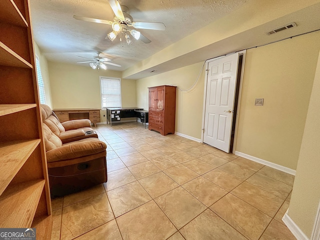 living room with ceiling fan, a textured ceiling, and light tile patterned floors