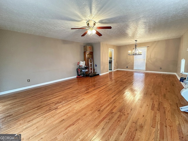 unfurnished living room featuring ceiling fan with notable chandelier, a textured ceiling, and light wood-type flooring