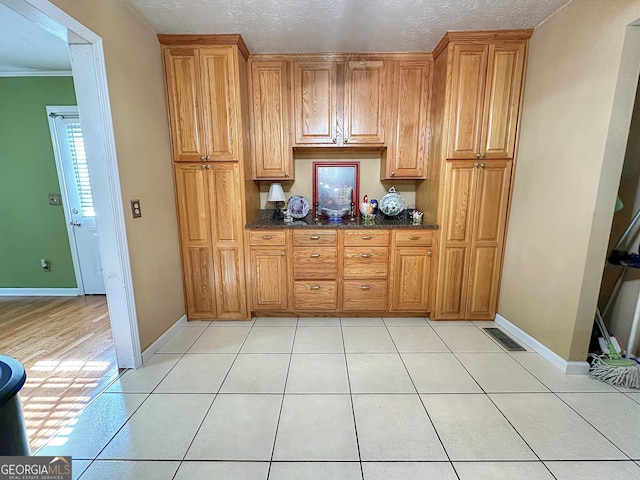 kitchen featuring dark stone counters, a textured ceiling, and light tile patterned flooring