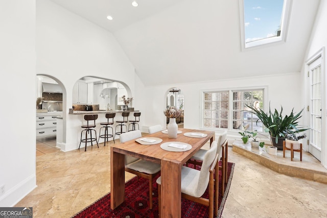 dining room with sink, a skylight, and high vaulted ceiling