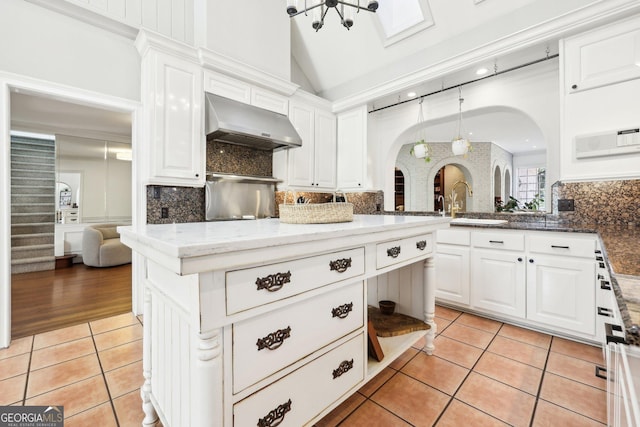 kitchen featuring dark stone counters, exhaust hood, white cabinets, and light tile patterned flooring