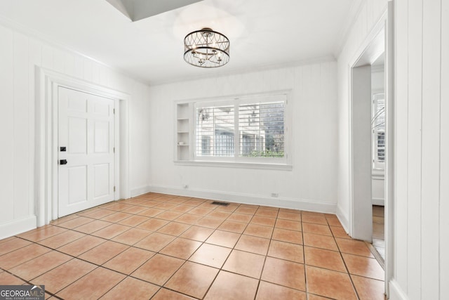 interior space featuring an inviting chandelier, ornamental molding, and light tile patterned flooring