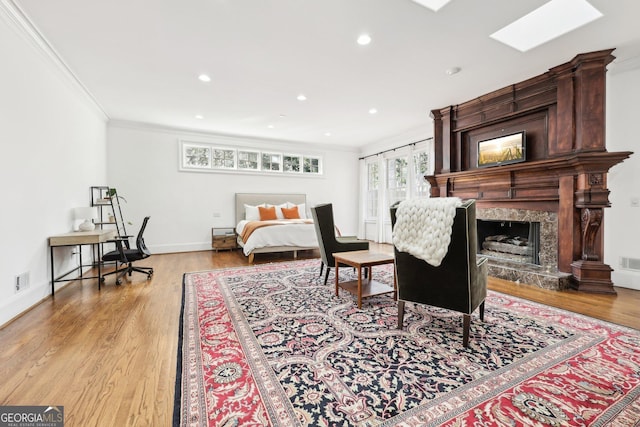 interior space with ornamental molding, a premium fireplace, a skylight, and light hardwood / wood-style flooring