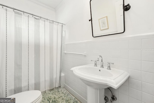 bathroom featuring toilet, sink, and tile walls