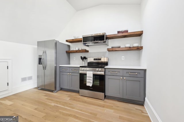 kitchen with lofted ceiling, gray cabinets, light hardwood / wood-style floors, and appliances with stainless steel finishes