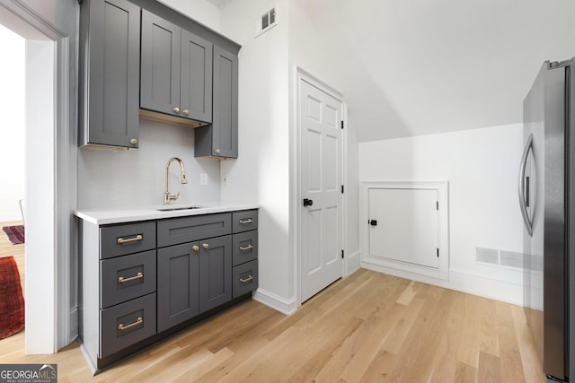 interior space featuring gray cabinetry, sink, light hardwood / wood-style floors, and stainless steel refrigerator