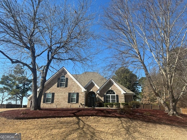 view of front of house with a front yard, fence, and brick siding