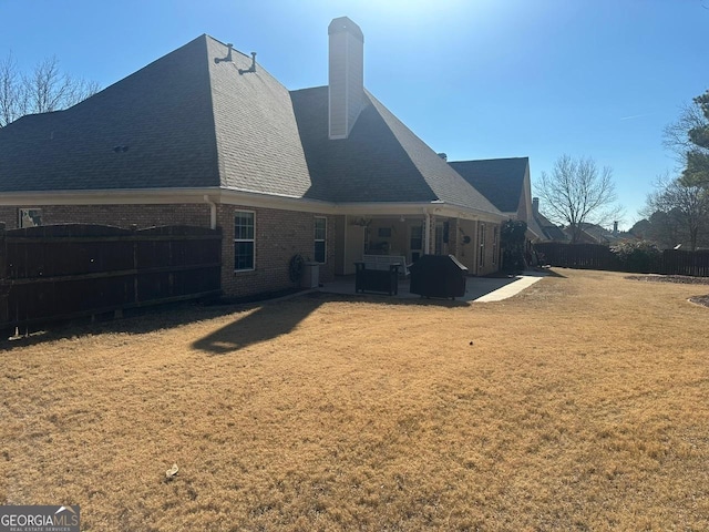 back of property with a yard and a patio area