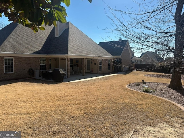 rear view of house with central AC unit, a lawn, and a patio