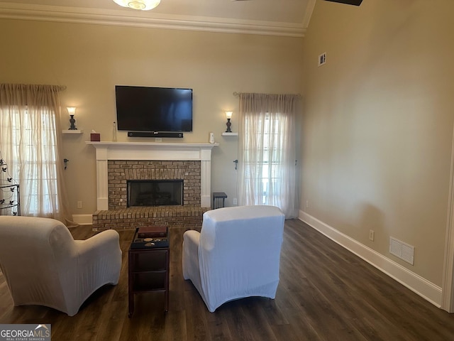 living room featuring dark wood-type flooring, ornamental molding, and a brick fireplace