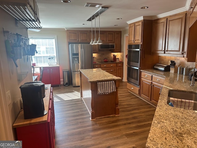 kitchen featuring dark wood-type flooring, stainless steel appliances, a center island, and hanging light fixtures