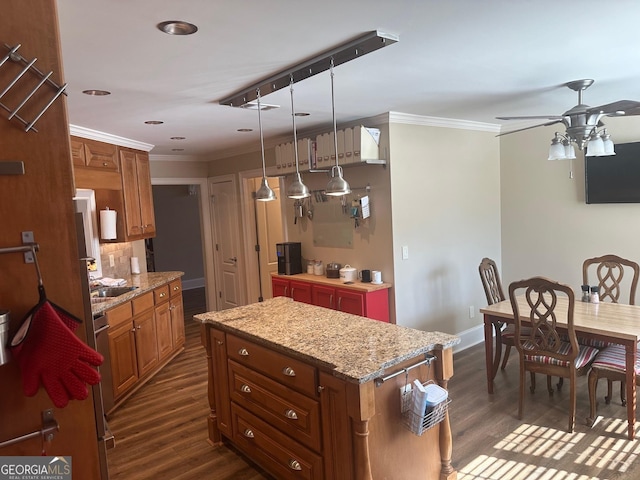 kitchen featuring crown molding, decorative light fixtures, light stone countertops, and a kitchen island