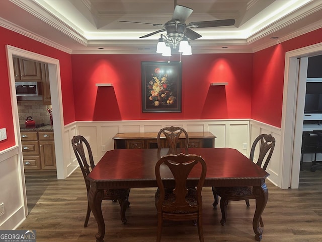 dining room featuring ceiling fan, ornamental molding, dark hardwood / wood-style floors, and a raised ceiling