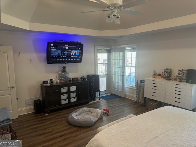 bedroom with dark wood-type flooring, a raised ceiling, and ceiling fan