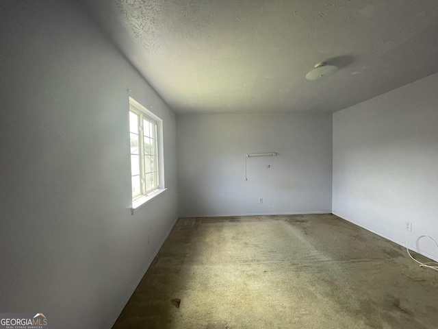 carpeted empty room featuring a textured ceiling