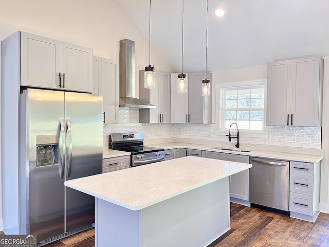 kitchen featuring vaulted ceiling, stainless steel appliances, gray cabinetry, wall chimney range hood, and a sink