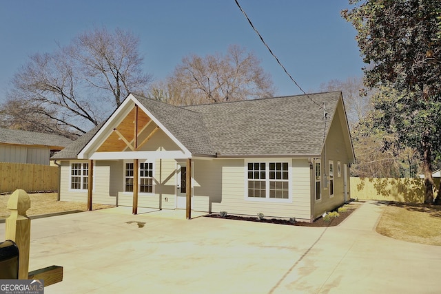 rear view of property featuring roof with shingles, a patio, and fence