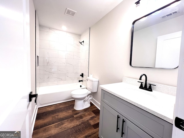 full bathroom with hardwood / wood-style flooring, vanity, tiled shower / bath combo, and toilet